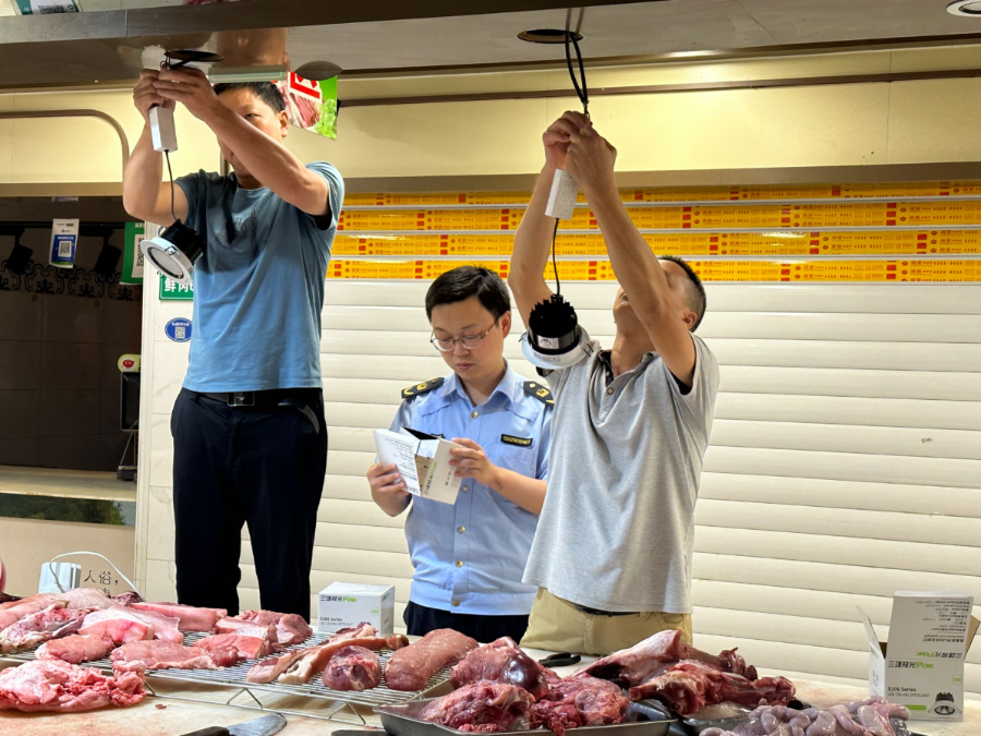 某農(nóng)貿(mào)市場內(nèi)，執(zhí)法人員檢查替換“生鮮燈”的燈具。湖里區(qū)市場監(jiān)督管理局供圖